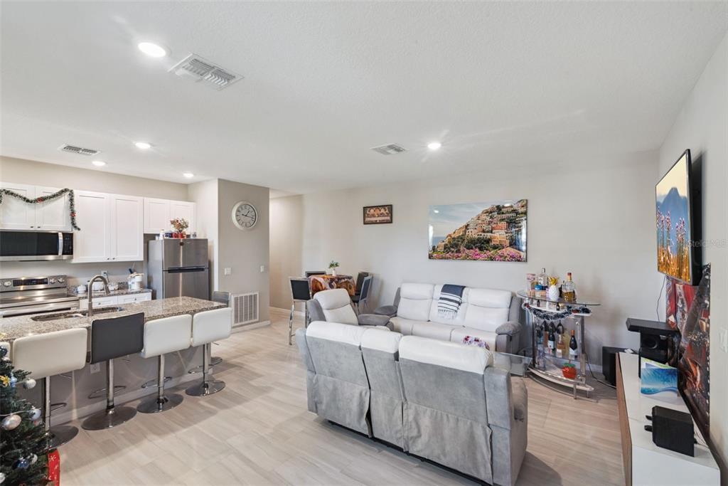 An open-concept kitchen and living area featuring white cabinets, a breakfast bar, and gray furniture — 1021/1023 TITCOMB STREET, EUSTIS, FL