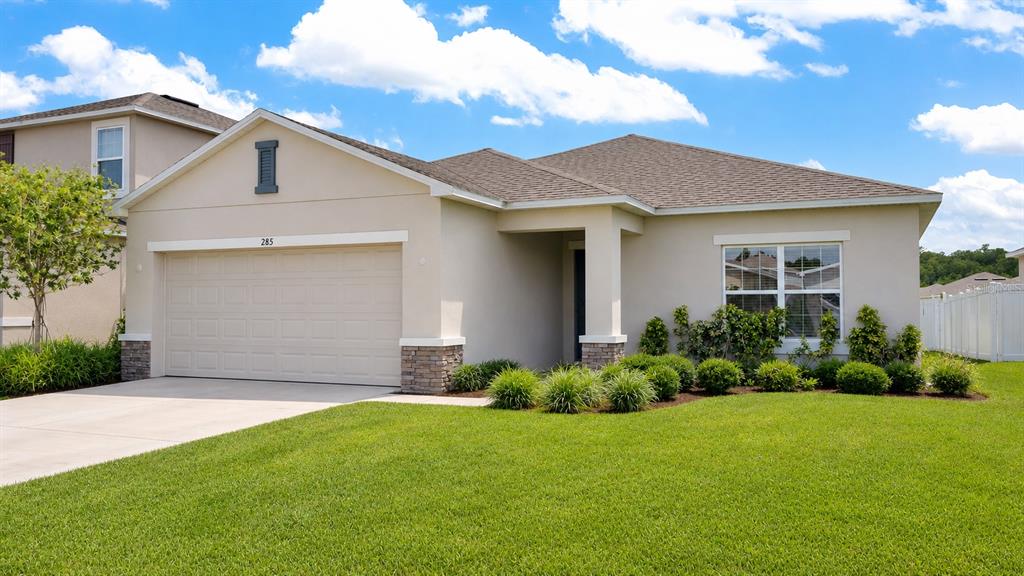 A single-story house with a beige stucco exterior, a two-car garage, and a front lawn — 285 WHITE HERON WAY, ST CLOUD, FL