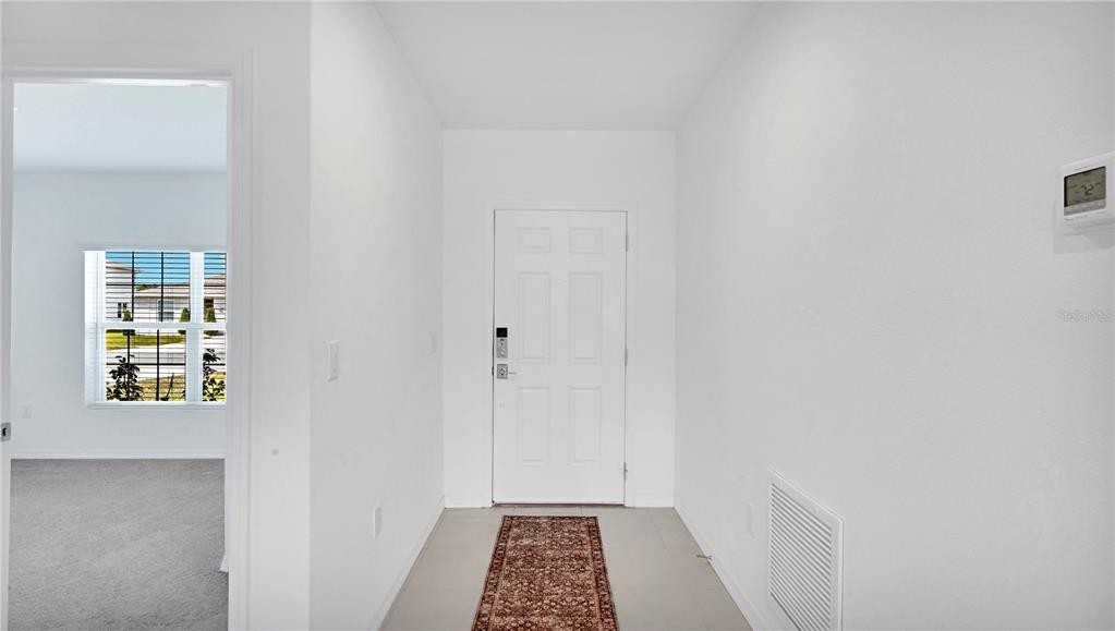 A white front door opens into a tiled entryway with a small rug — 285 WHITE HERON WAY, ST CLOUD, FL