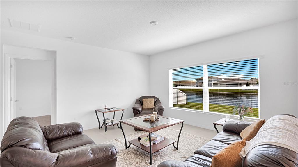 A living room with leather furniture, a glass-top coffee table, and a view of water — 285 WHITE HERON WAY, ST CLOUD, FL