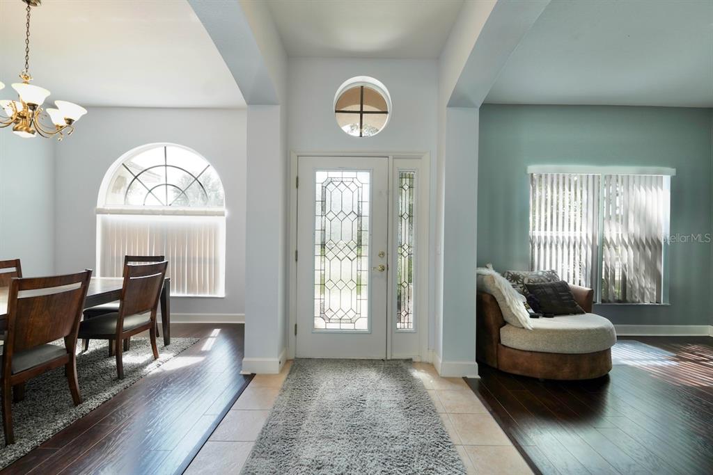 An entryway with a glass-paneled front door, tile flooring, and adjacent dining and living areas — 5683 BRACKENWOOD DRIVE, SPRING HILL, FL