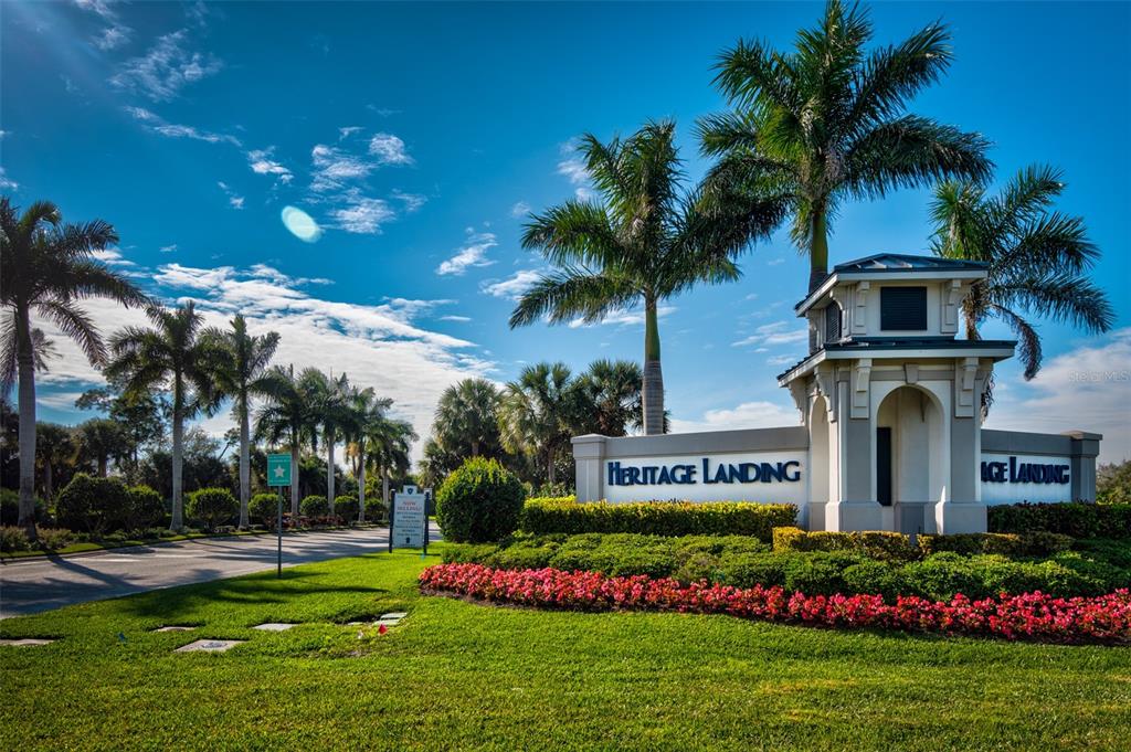 The entrance sign for Heritage Landing features palm trees and a landscaped garden — 14132 POPPY FIELD LOOP UNIT 4022, PUNTA GORDA, FL