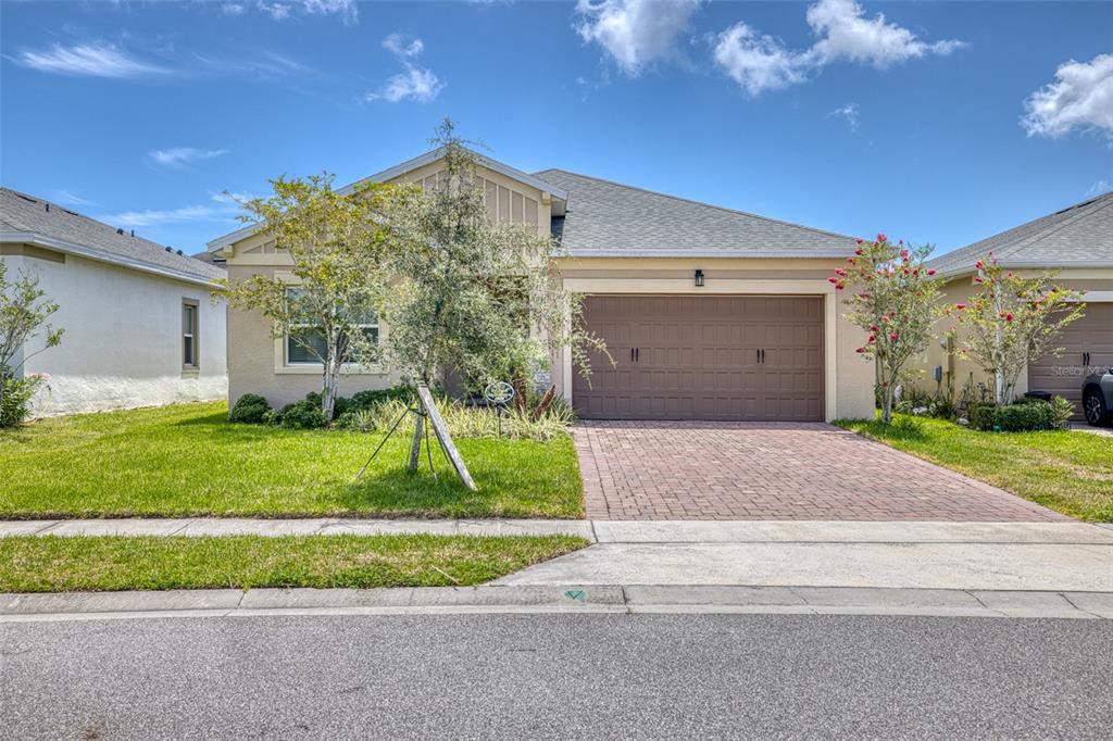 A single-story suburban house features a brown garage door, a brick driveway, and a front lawn — 5303 CALADESI, PORT ORANGE, FL