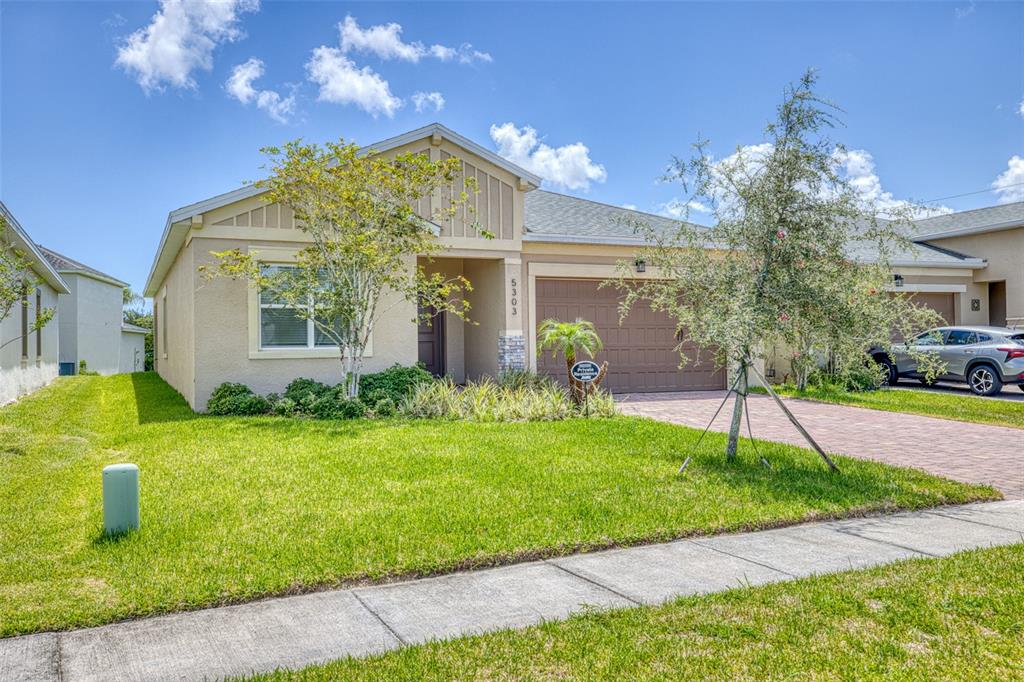 A single-story suburban house with a tan stucco exterior, a two-car garage, and a lawn — 5303 CALADESI, PORT ORANGE, FL