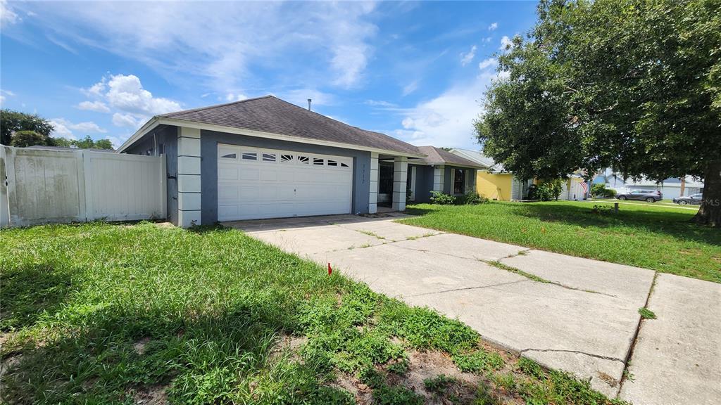 A single-story house with a white garage door, gray siding, and a concrete driveway — 7712 SIMON RIDGE COURT, KISSIMMEE, FL