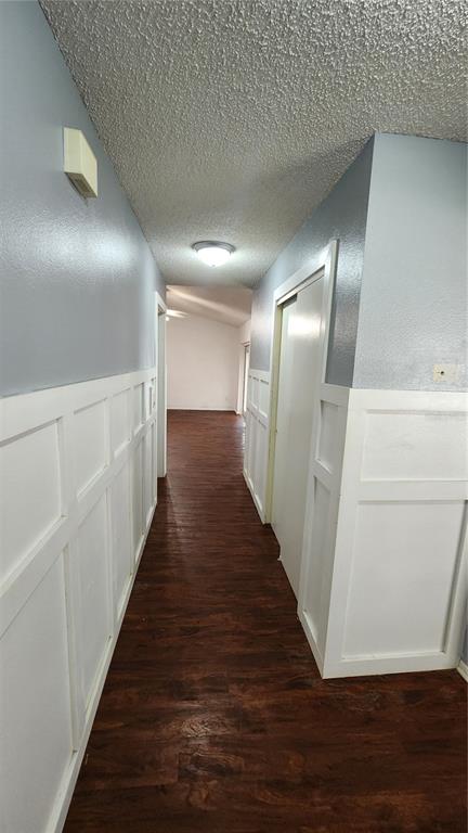A hallway with wood-look flooring, white wainscoting, and light blue walls leads to another room — 7712 SIMON RIDGE COURT, KISSIMMEE, FL