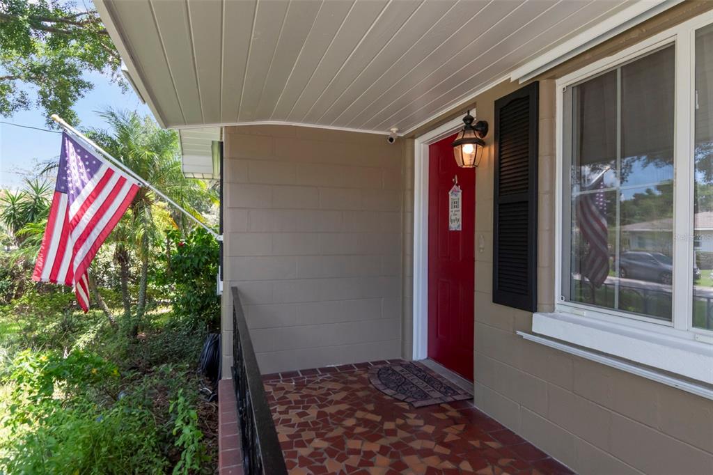 A covered front porch features a red door, a tiled floor, and an American flag — 311 N GOMEZ AVENUE, TAMPA, FL