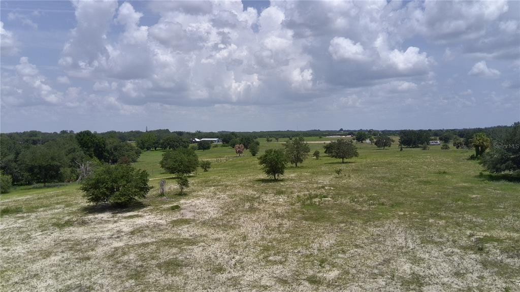 An aerial view of a large, grassy, sandy field with scattered trees under a cloudy sky — 4547 GLEN SAINT MARY RD ROAD, LAKE WALES, FL