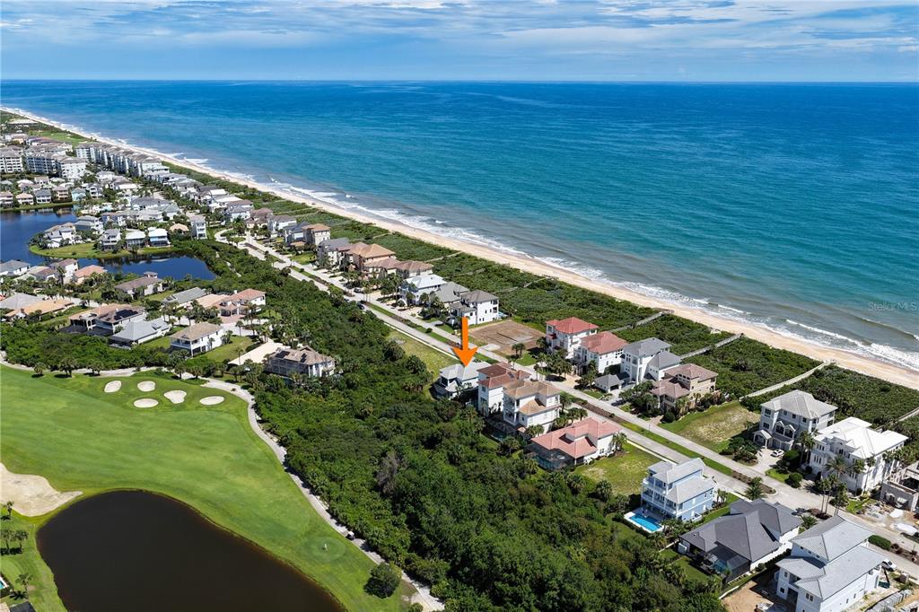 An aerial view shows a coastal neighborhood with houses situated between a golf course and beach — 23 OCEAN RIDGE BOULEVARD N, PALM COAST, FL