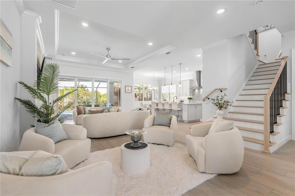 A bright, open-concept living room and kitchen featuring light wood floors and a staircase — 23 OCEAN RIDGE BOULEVARD N, PALM COAST, FL