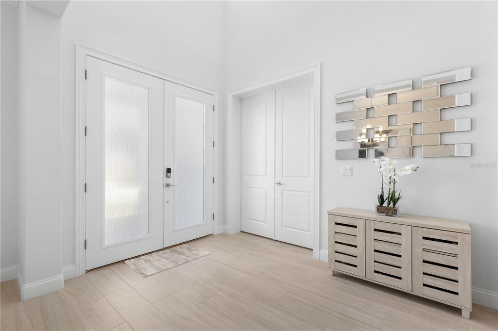A bright entryway features white double doors, light wood-look flooring, and a modern console table — 23 OCEAN RIDGE BOULEVARD N, PALM COAST, FL