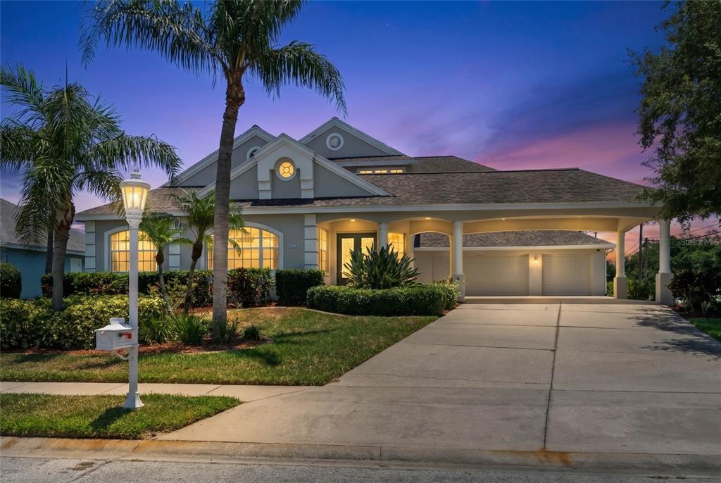 A single-story house with a covered driveway, palm trees, and a sunset sky — 4306 BARRACUDA DRIVE, BRADENTON, FL