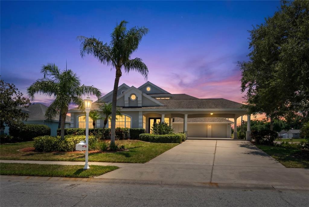 A single-story house with a carport, palm trees, and a concrete driveway at sunset — 4306 BARRACUDA DRIVE, BRADENTON, FL