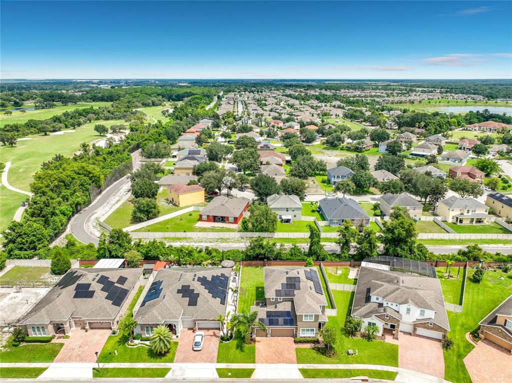An aerial view shows a suburban neighborhood with houses featuring solar panels on their roofs — 1083 DUSTY PINE DRIVE, APOPKA, FL