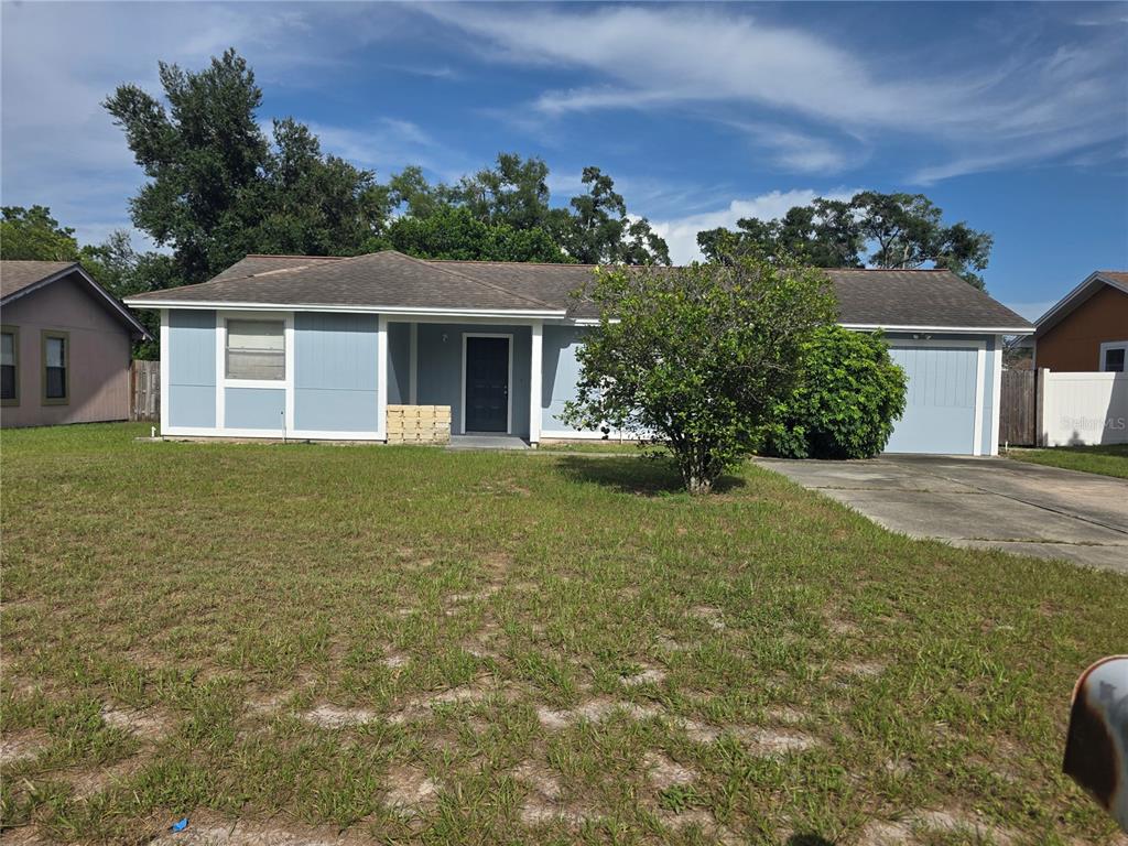 A single-story house with light blue siding, a dark roof, and a front-facing garage — 8507 CALADESI ISLAND DRIVE, TEMPLE TERRACE, FL