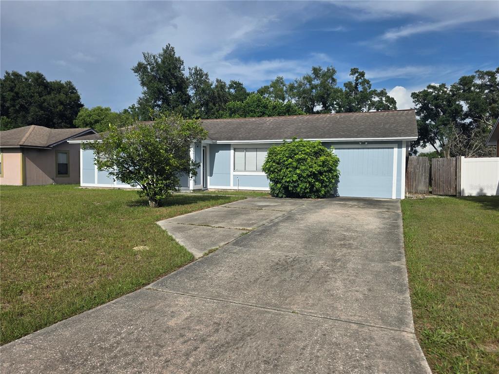 A single-story light blue house features a concrete driveway, a garage, and a front lawn — 8507 CALADESI ISLAND DRIVE, TEMPLE TERRACE, FL