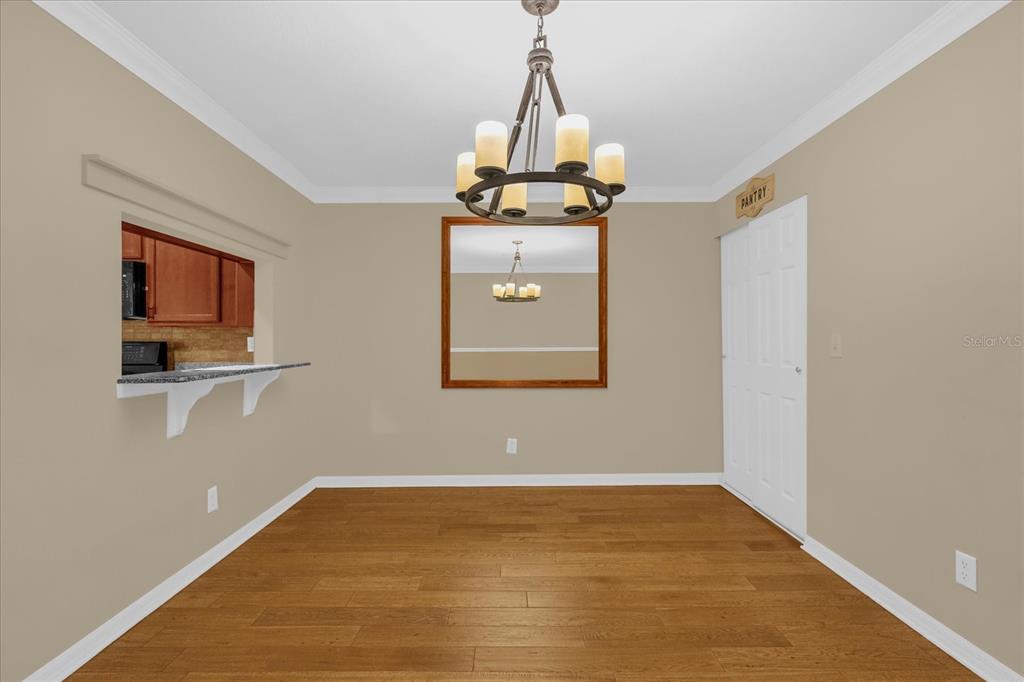 A dining room features wood-look flooring, a central chandelier, a wall mirror, and a pantry door — 5440 RIVER ROCK ROAD UNIT 5440, LAKELAND, FL