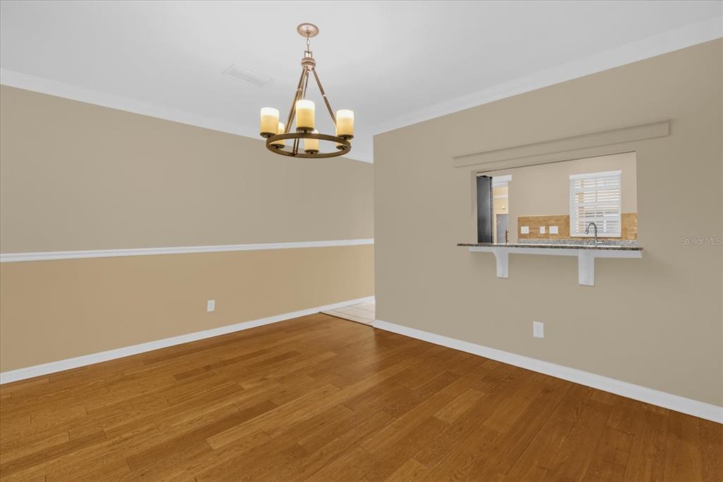 A dining room with wood flooring, a chandelier, and a pass-through window to the kitchen — 5440 RIVER ROCK ROAD UNIT 5440, LAKELAND, FL