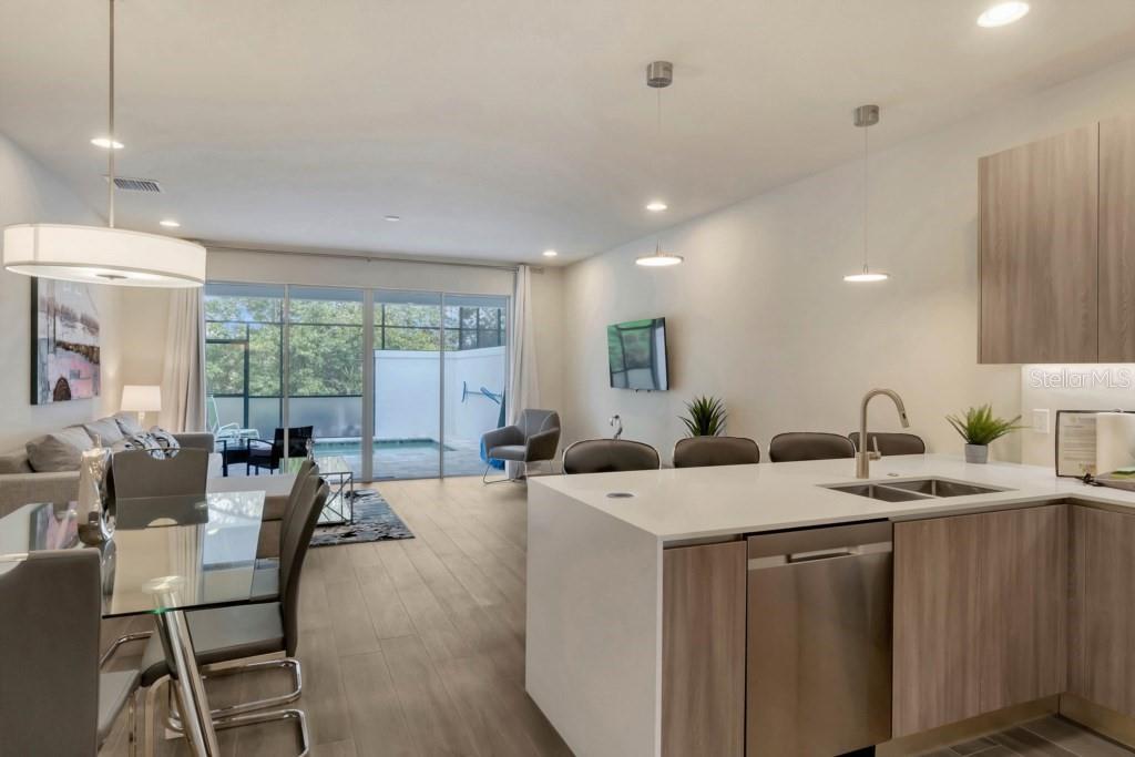 An open-concept kitchen and living area with a glass dining table and a backyard pool — 17305 HIDDEN FOREST DRIVE, CLERMONT, FL