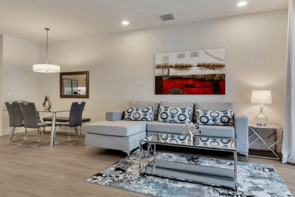 A living room features a gray sectional sofa, a glass coffee table, and a dining area — 17305 HIDDEN FOREST DRIVE, CLERMONT, FL
