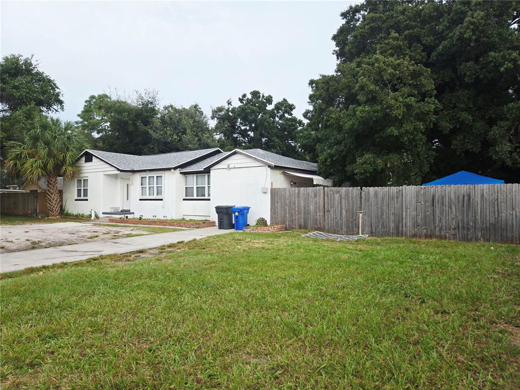 A white single-story house with a gray roof sits behind a wooden fence and lawn — 3119 W LAMBRIGHT STREET, TAMPA, FL
