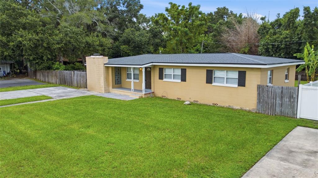 A single-story tan house with a flat roof, front porch, and a large grassy yard — 3519 CALUMET DRIVE, ORLANDO, FL