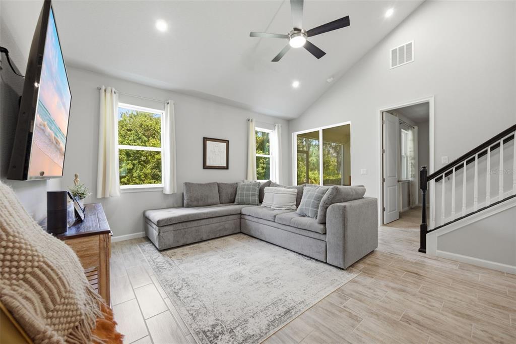A modern kitchen with white cabinets, stainless steel appliances, and an island with bar stools — 5636 SILVERBRIDGE TRAIL, BRADENTON, FL