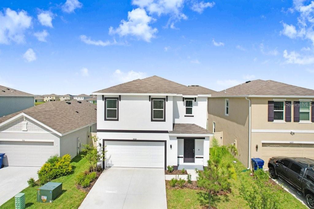 A two-story suburban house with a white exterior, dark trim, and a two-car garage — 9319 FORGE BREEZE LOOP, WESLEY CHAPEL, FL