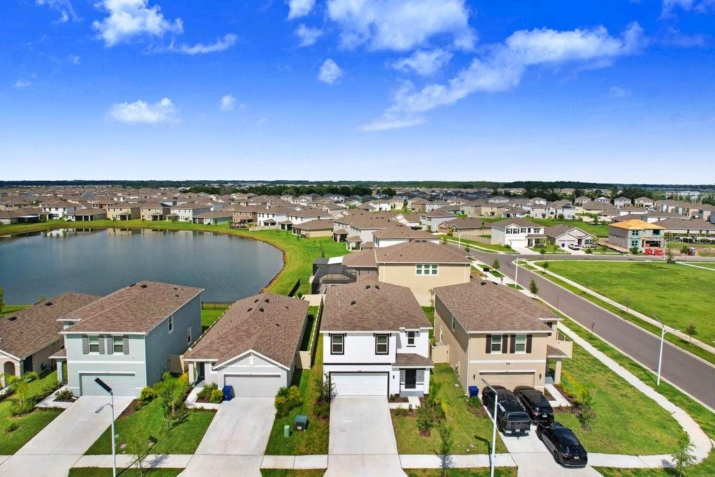 An aerial view of a suburban neighborhood featuring houses, a pond, and paved streets — 9319 FORGE BREEZE LOOP, WESLEY CHAPEL, FL