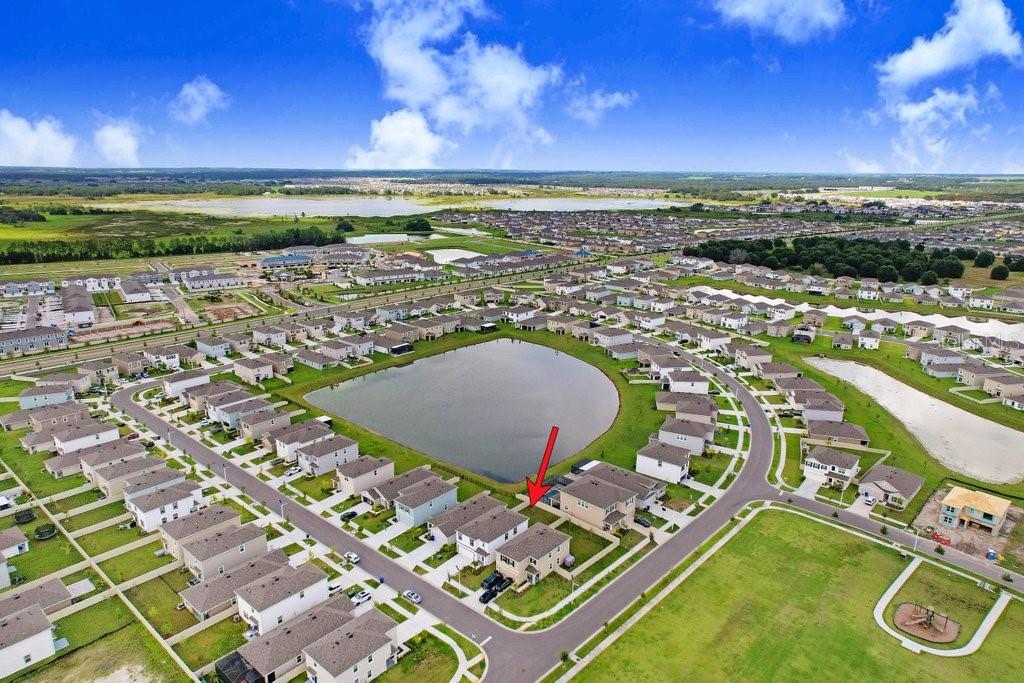 An aerial view of a suburban neighborhood featuring a central pond and residential houses — 9319 FORGE BREEZE LOOP, WESLEY CHAPEL, FL