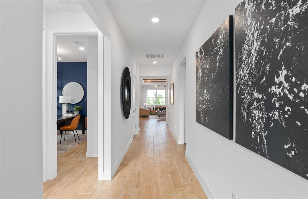 A bright hallway with light wood-look tile floors leads toward a living area — 2222 BRANCHED OAK ROAD, ST CLOUD, FL