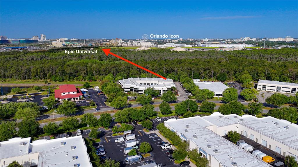 An aerial view shows commercial buildings, parking lots, and surrounding trees with distant city landmarks — 8615 COMMODITY CIRCLE UNIT 2, ORLANDO, FL