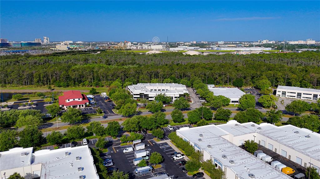 An aerial view shows several commercial office buildings surrounded by parking lots and wooded areas — 8615 COMMODITY CIRCLE UNIT 2, ORLANDO, FL
