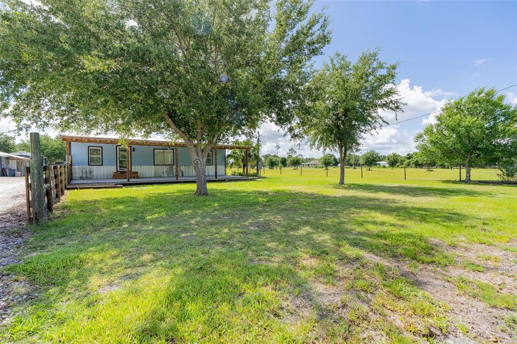 A single-story house with a covered porch sits on a large, grassy, tree-filled lot — 10876 SW WALKER ROAD, ARCADIA, FL