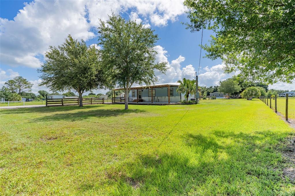 A single-story house with a covered porch sits on a large, grassy, fenced-in lot — 10876 SW WALKER ROAD, ARCADIA, FL