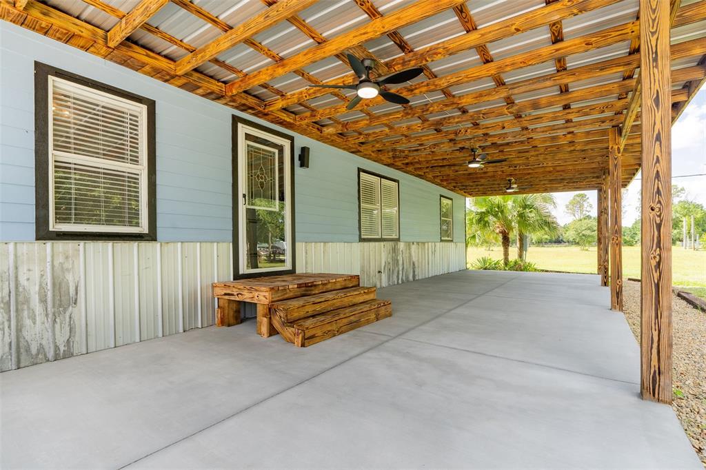 A covered concrete patio features a wooden ceiling, ceiling fans, and steps to a door — 10876 SW WALKER ROAD, ARCADIA, FL