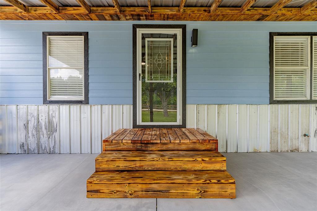 A wooden three-step staircase leads to a glass-paneled door on a light blue house exterior — 10876 SW WALKER ROAD, ARCADIA, FL