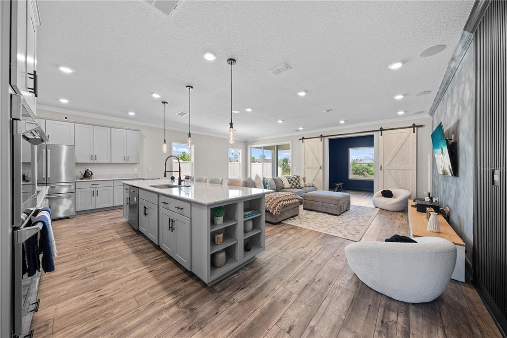 A modern open-concept kitchen and living area with light gray cabinetry and wood-look flooring — 31041 JAZZ LEAF PLACE, SAN ANTONIO, FL