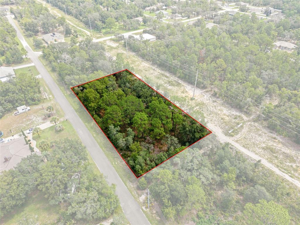 An aerial view shows a rectangular, wooded vacant lot outlined in red along a paved road — 12250 MARVELWOOD ROAD, WEEKI WACHEE, FL