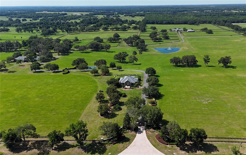 An aerial view shows a house surrounded by large green pastures, trees, and a pond — 6800 SE 193RD STREET, MICANOPY, FL