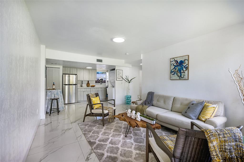 A living room with white marble-look tile floors, a neutral sofa, and an open kitchen — 431 N EAST AVENUE, SARASOTA, FL