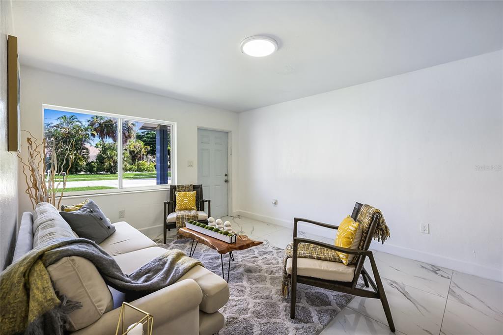 A living room features white walls, marble-look tile floors, a sofa, two armchairs, and a window — 431 N EAST AVENUE, SARASOTA, FL