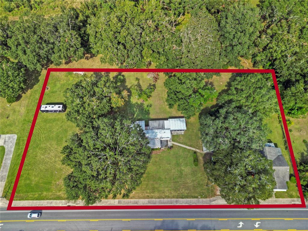 An aerial view shows a house on a large, tree-filled lot bordering a road — 3778 E C-466 ROAD, OXFORD, FL