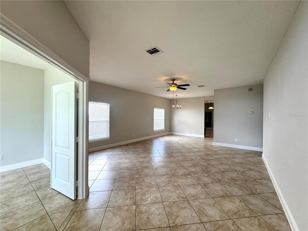 An open-concept living area features light-colored walls, tile flooring, and a ceiling fan — 11273 MOONSHINE CREEK CIRCLE, ORLANDO, FL