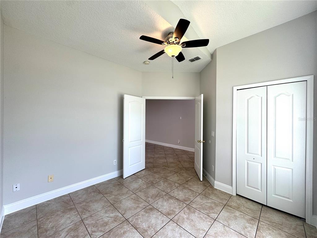 A room with tile flooring, a ceiling fan, and double doors leading to another space — 11273 MOONSHINE CREEK CIRCLE, ORLANDO, FL