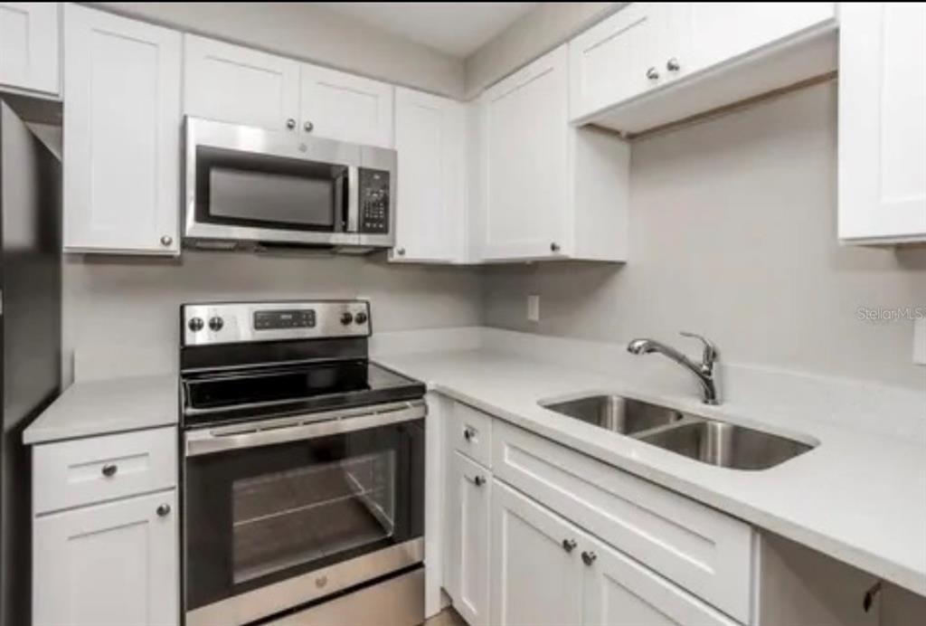 A kitchen features white cabinets, stainless steel appliances, a double sink, and light-colored countertops — 918 VALMAR STREET, BRANDON, FL
