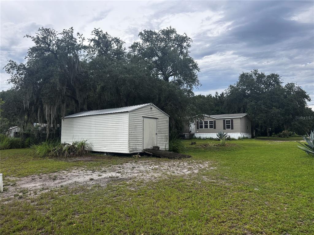 A white storage shed sits on a grassy lot in front of a mobile home — 15080 NE 242ND AVENUE, SALT SPRINGS, FL