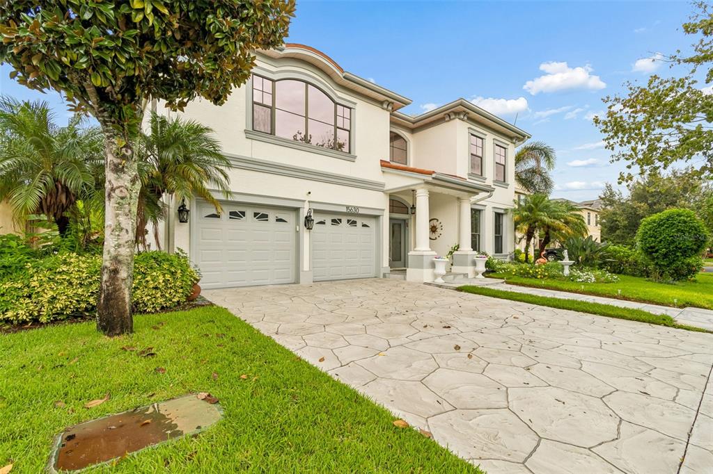 A two-story house with a light-colored stucco exterior, a stone driveway, and a two-car garage — 15630 N HIMES AVENUE, TAMPA, FL