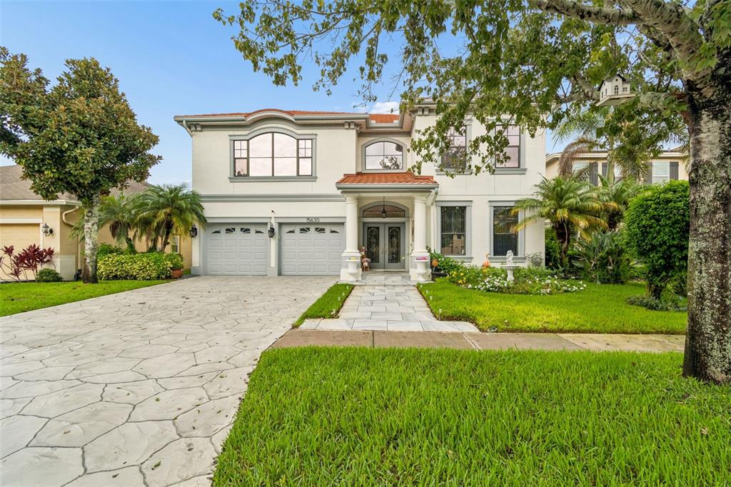 A two-story house with a light-colored exterior, a tiled roof, and a stone-paved driveway — 15630 N HIMES AVENUE, TAMPA, FL