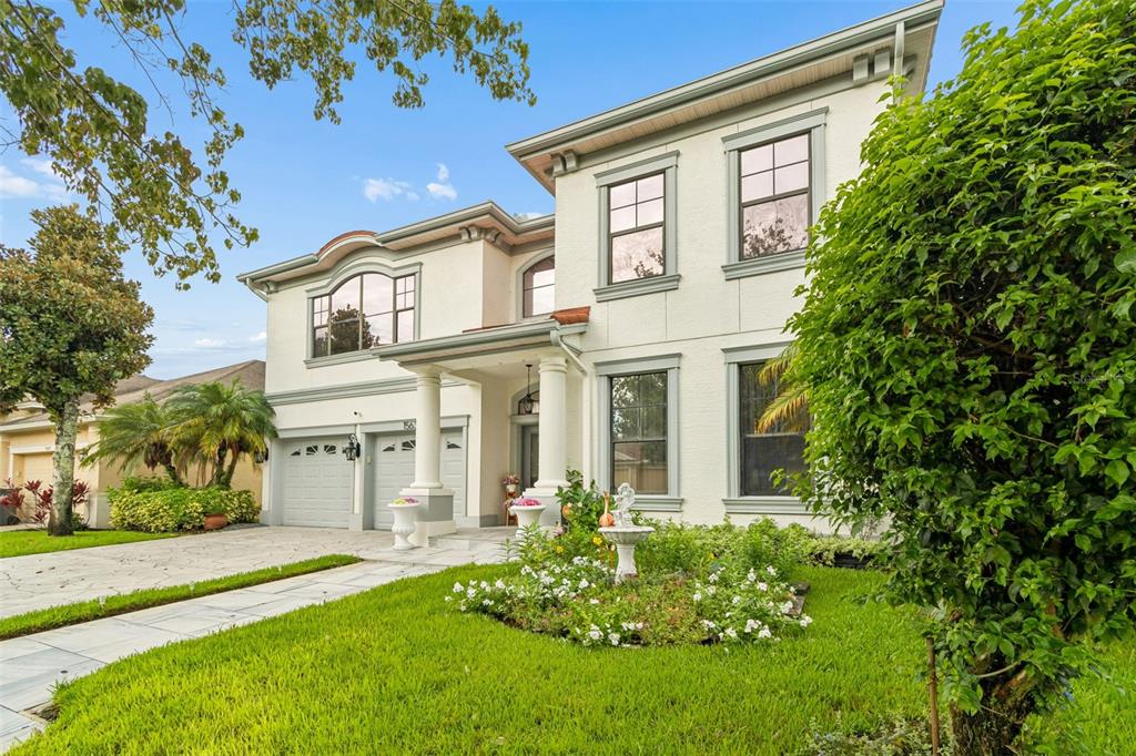 A two-story stucco house with a multi-car garage, front columns, and a landscaped front yard — 15630 N HIMES AVENUE, TAMPA, FL